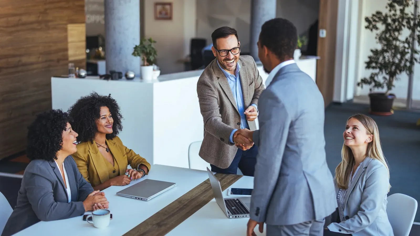 A hiring manager and a candidate shaking hands in a meeting room